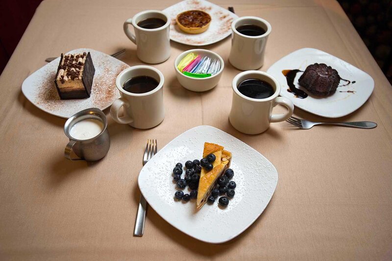 Assorted desserts and coffee mugs with focus on blueberry pie